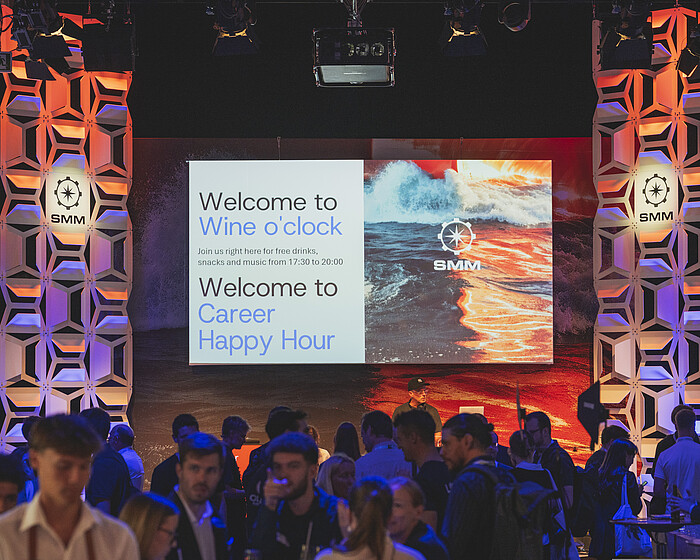 Abendveranstaltung auf der SMM mit zahlreichen Gästen vor einer beleuchteten Bühne und einer großen Leinwand zur „Wine o’clock“ und „Career Happy Hour“.