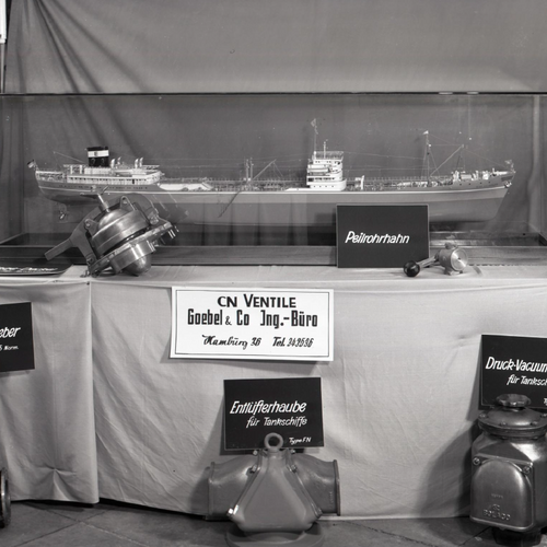 Ein historisches Bild eines Tisches mit einem Miniaturschiff und mehreren kleinen Schiffsteilen von CN Ventile Goebel & Co.