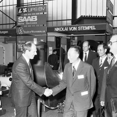 Ein Schwarz-Weiß-Bild von einer früheren Messe, auf dem zwei Männer sich die Hände schütteln