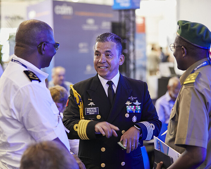 Drei Personen unterhalten sich auf der Messe miteinander und stehen beisammen.