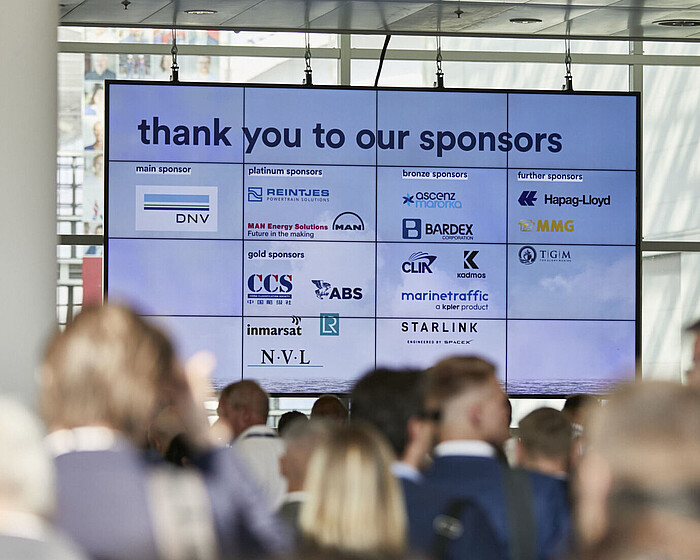 Eingangsbereich auf der SMM, es ist Menschenmenge zu sehen sowie eine digitale Anzeige mit Sponsoren. 