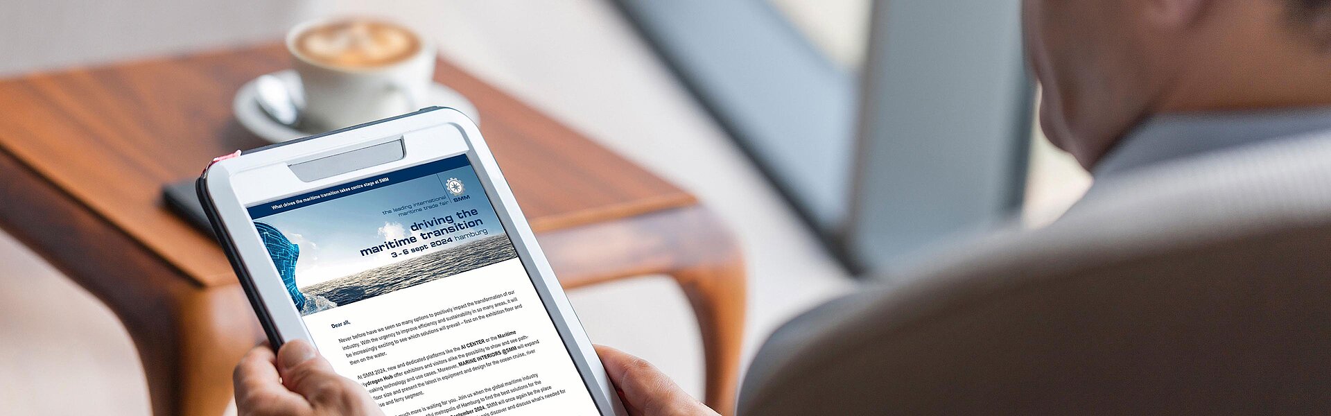 Blick über die Schulter eines Mannes auf ein Tablet mit den News der SMM.